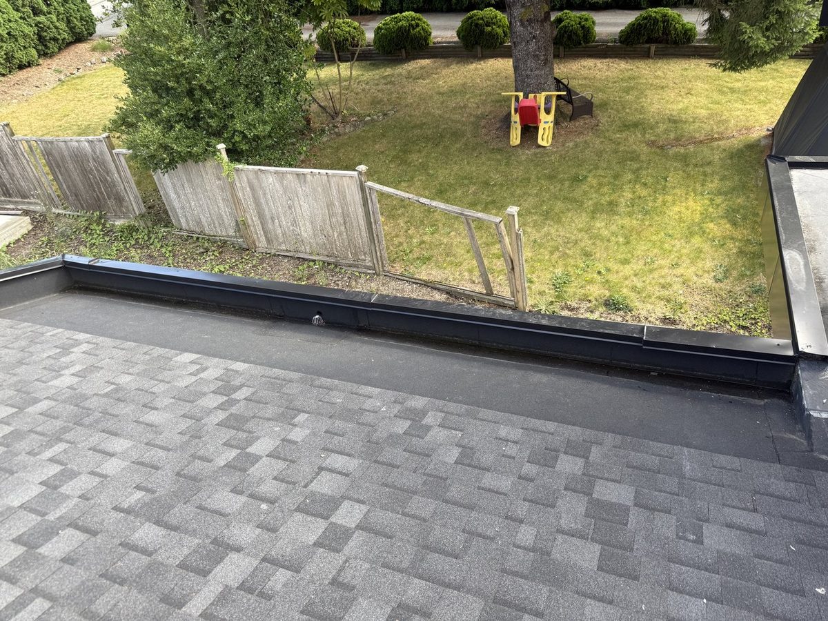 Finished asphalt shingle roof beside a flat roof edge